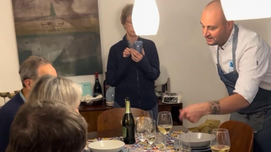 Chef seated at a dining table in Sicily, sharing a moment of traditional Sicilian food and hospitality.